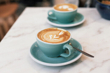 Two cups of flat white coffee on a marble table in a cafe