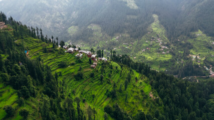 aerial top down of Jibhi mountains on cloudy afternoon and homes overlooking the valley