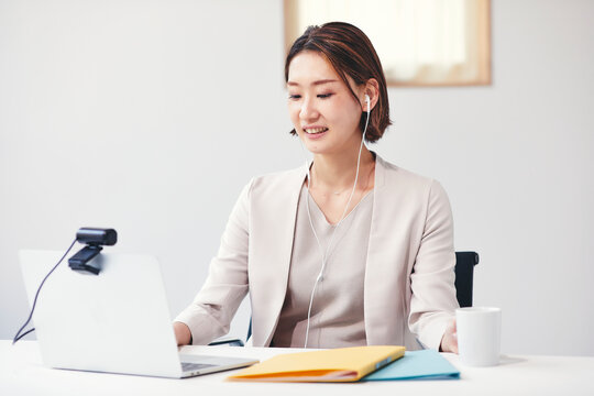 カメラに向かって話すスーツを着た若い男性とパソコン