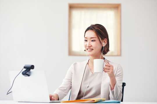 カメラに向かって話すスーツを着た若いビジネスウーマンとパソコン