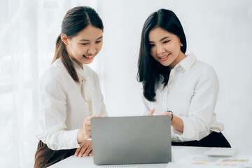Two business Asian young women working together with laptop computer in the modern office.