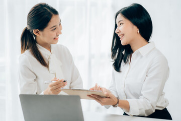 Fototapeta premium Two business Asian young women working together with laptop computer in the modern office.