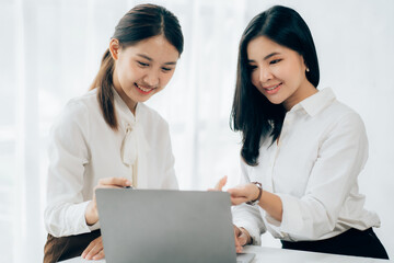 Two business Asian young women working together with laptop computer in the modern office.