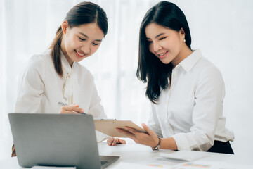 Obraz premium Two business Asian young women working together with laptop computer in the modern office.
