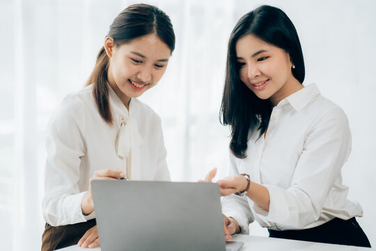 Two business Asian young women working together with laptop computer in the modern office.