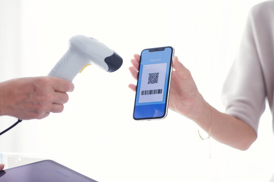 レジでスマートフォンを持ちキャッシュレス決済をする若い女性