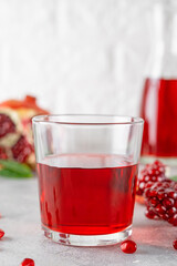 A glass of pomegranate juice with fresh pomegranate fruits on a gray concrete background. Vitamins and minerals. Healthy drink concept. Copy space.