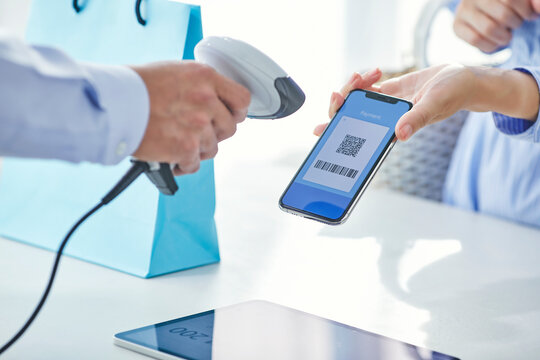 スマートフォンを持ちキャッシュレス決済をする女性の手元と店員の手