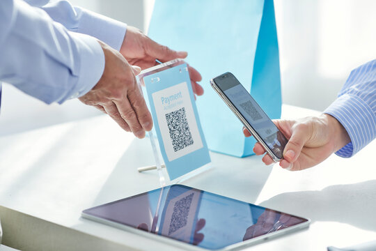 スマートフォンを持ちキャッシュレス決済をする女性の手元と店員の手