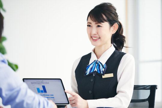 制服を着てタブレット端末を使い説明をする女性