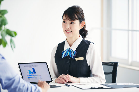 制服を着てタブレット端末を使い説明をする女性