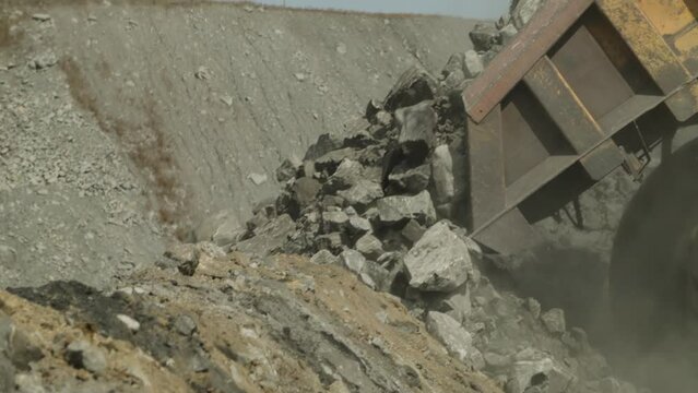 Multi-ton dump truck lifts body, unloads waste rock and leaves. Close up view. Element of coal mining process