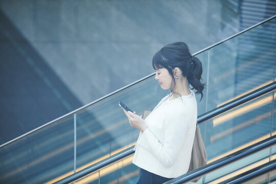 スマホを持ち屋外を歩くビジネスウーマン