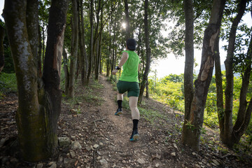 Fototapeta premium Woman trail runner running at sunrise tropical forest mountain peak