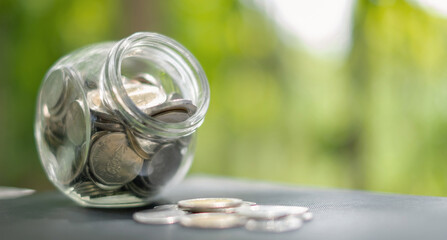 Retirement savings concept. bottle glass and coins with green nature background and copy space
