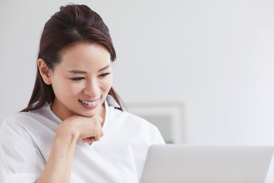 ノートパソコンを使い部屋で仕事をする女性