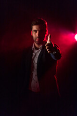 Photo of standing man showing thumb up and pink light on the background.