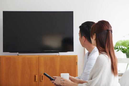 リビングでテレビを観ながらくつろぐ女性と男性