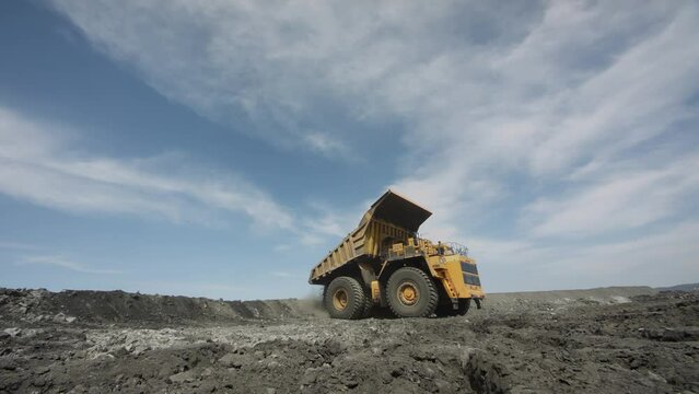 Multi-ton dump truck lifts body, unloads waste rock and leaves. Element of coal mining process
