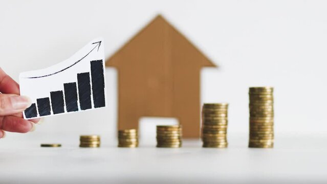 interest rates for loans and real estate prices going up, graph with upward trend with growing stacks of coins in front of cardboard house