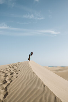 Woman standing on sand land and blue sky at sunset