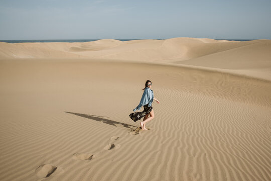 Woman standing on sand land and blue sky at sunset
