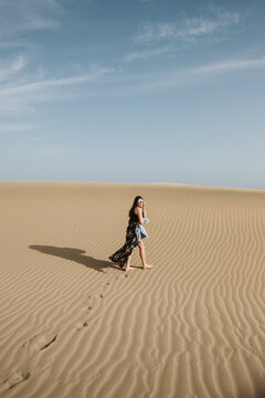 Woman standing on sand land and blue sky at sunset