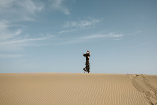 Woman standing on sand land and blue sky at sunset