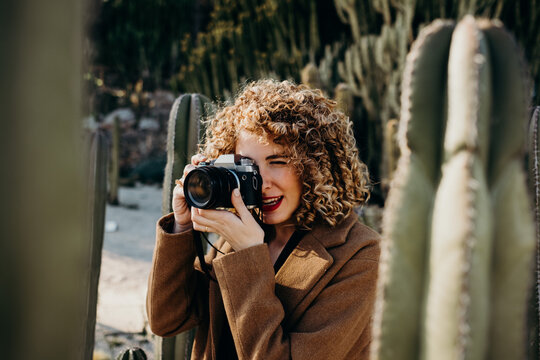 Portrait of beautiful curly blonde woman using a retro camera