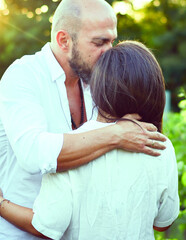 Portrait of a Smiling  happy Couple Kissing    in a Vineyard toasting wine. Beautiful  brunette woman and bearded muscular man spending time together during grape harvest.