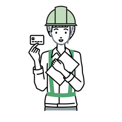 立って書類とカードを手に持つ工事現場の女性