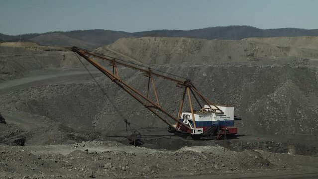 Career walking excavator removes waste rock, digging out layer of useful material. Coal quarry in Russia.