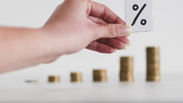 interest rates for loans and mortgages going up, percentage symbol with growing stacks of coins representing increasingly expensive cost of financing