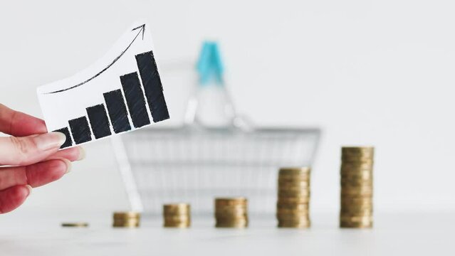 rising inflation graph in front of shopping basket and growing stacks of coins representing increasingly expensive prices, global economy struggling after the covid-19 pandemic
