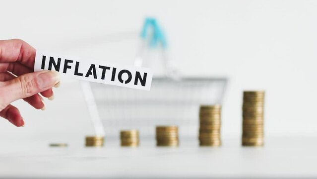 inflation text with shopping baset and growing stacks of coins representing increasingly expensive prices, global economy struggling after the covid-19 pandemic