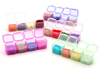 Creative flatlay of different seed and pearl beads in the box on pink background.