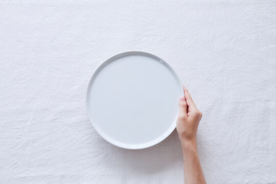 白い皿を持つ女性の手