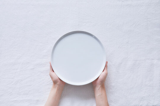 白い皿を持つ女性の手