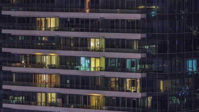 Windows lights in modern residential buildings timelapse at night. Multi-level skyscrapers with illuminated rooms inside