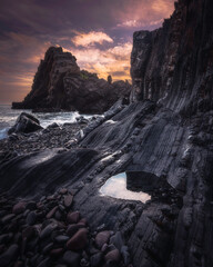 Sunrise over Black Church rock on the coast of Devon, UK. Beautiful morning landscape scene with the colourful cloudy sky over the rocky beach with the rock formation.