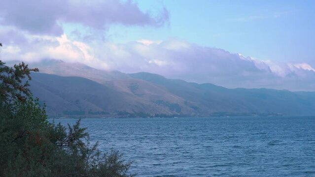 Close view lake with mountains background. Sevan lake in Armenia. White clouds on blue sky.