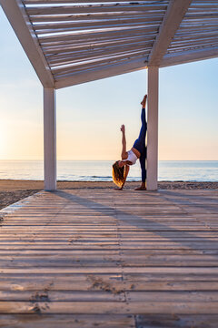 Woman doing yoga in standing split pose at seaside