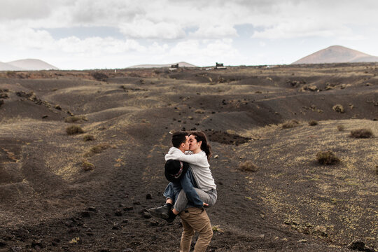 Traveling young couple kissing against picturesque volcano landscape