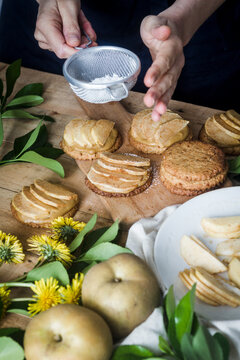 Crop Person Spilling Icing Sugar On Tartlets