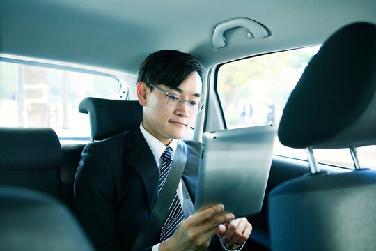 車に乗りタブレットPCを見るビジネスマン
