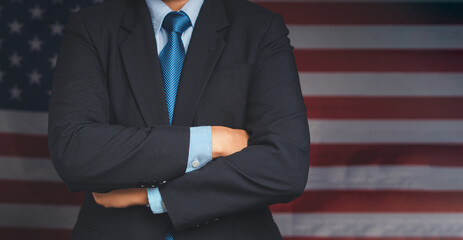 Midsection of a businessman in a suit while standing with arms crossed against USA flag background