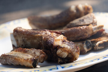 Close-up with defocused background of pork ribs cooked on a wood-fired grill