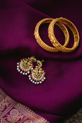 Golden bangles with Gold earrings on a purple saree background 