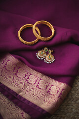 Golden bangles with Gold earrings on a purple saree background 