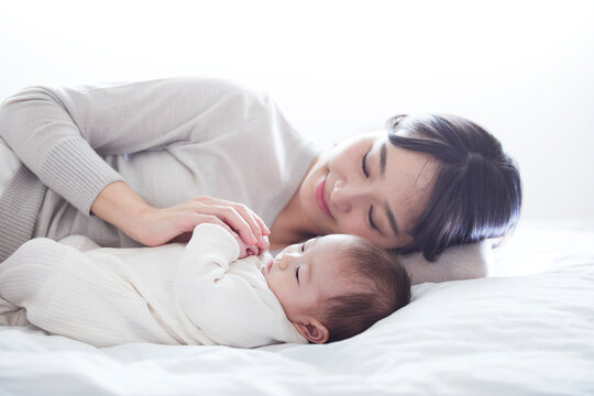 眠る赤ちゃんと添い寝をする母親